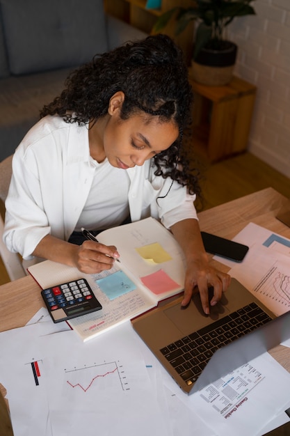 A close-up of a Colombian entrepreneur working on a laptop, surrounded by financial documents and graphs, symbolizing the analysis and planning required to leverage tax incentives effectively.