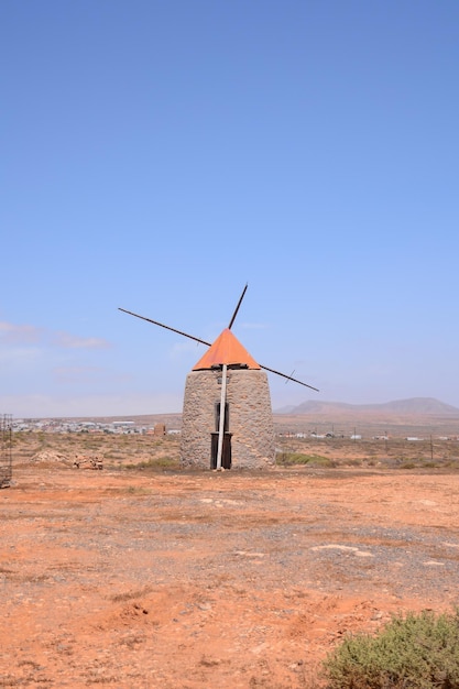 A close-up shot of a wind turbine turning in a wind farm in La Guajira, Colombia, with the arid landscape stretching into the horizon. Focus on the turbine blades and the clear blue sky.