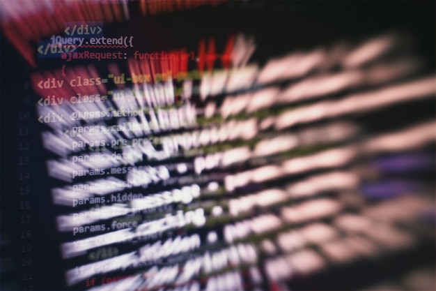 A close-up of a computer screen displaying lines of code, with a blurred background of other developers in a co-working space in Medellín, Colombia. The focus should be on the code and the hands typing on the keyboard.