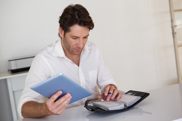 A person carefully reviewing a list of tax deductions and benefits on a tablet, with a calculator and financial documents nearby.
