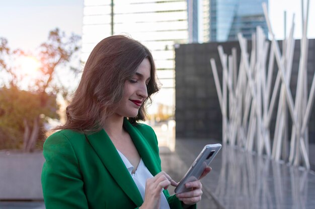 A person is reviewing a financial chart with growing green lines, while standing in front of a skyscraper in Medellin, Colombia.