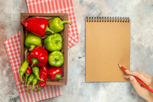 A kitchen counter with a variety of fresh fruits and vegetables arranged neatly, next to a handwritten meal plan and shopping list. A person's hand is reaching for a red apple.