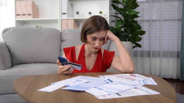 A stressed individual looking at a pile of bills and a credit card statement, highlighting the challenges of managing debt.