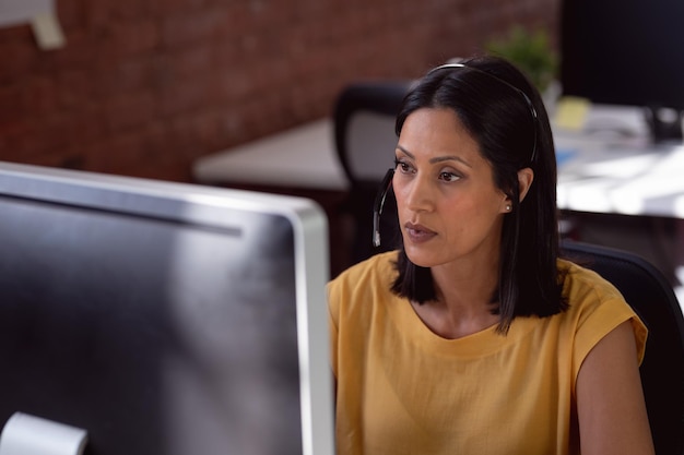 A woman in a Colombian office setting looking worried at her computer, representing job insecurity.