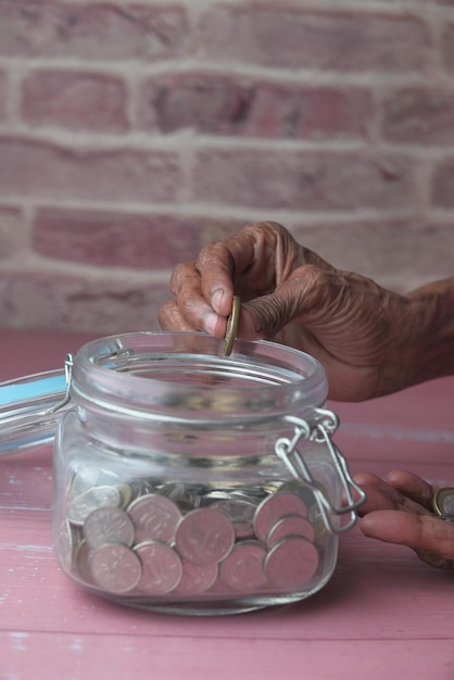Hands sorting Colombian pesos into different labeled jars - 