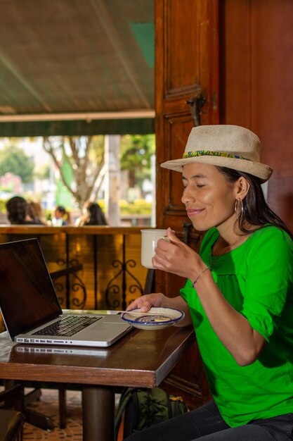 A Colombian citizen checking their credit score on a laptop, with a serious expression, in a brightly lit cafe.