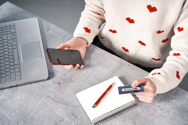 A person confidently using a credit card and laptop at a modern desk, with a financial planning notebook open beside them. The scene should convey responsible financial management.