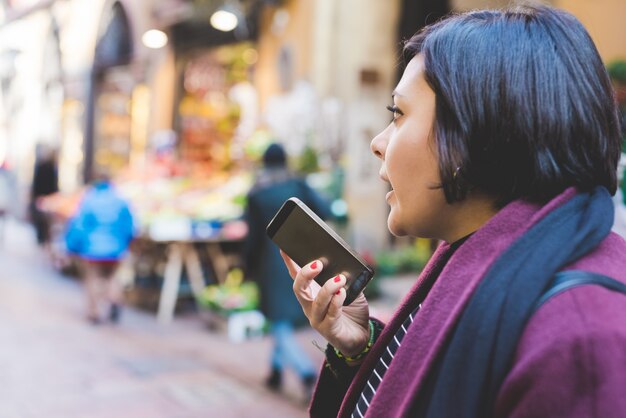 A person using a smartphone to check their credit score online, with a concerned expression on their face. The background is blurred, showing a typical Colombian street scene.