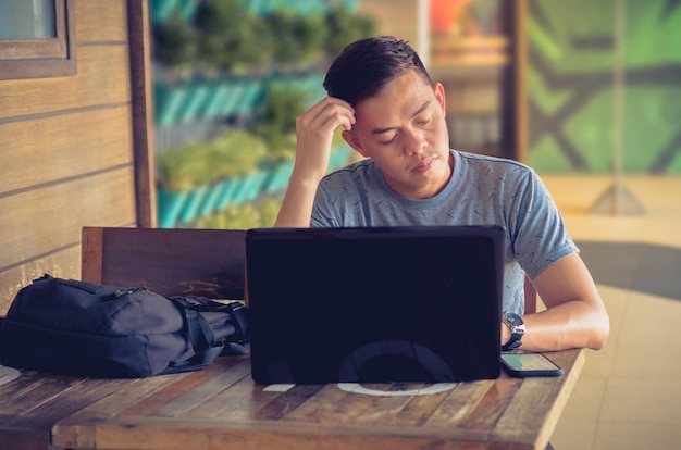 A stressed young man in Colombia looks at his laptop, concerned about his credit score. Charts and graphs on the screen show a declining credit rating. He is holding his head in his hands, worried about his ability to rent an apartment.