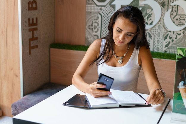 A Colombian woman uses a budgeting app on her smartphone to manage her finances. The app displays various pie charts and graphs showing her income, expenses, and debt payments. She looks focused and determined to improve her credit score.