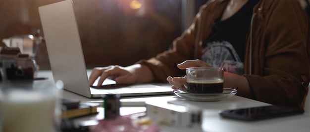 A person working on a laptop at a coffee shop, highlighting the concept of freelance work and generating additional income.