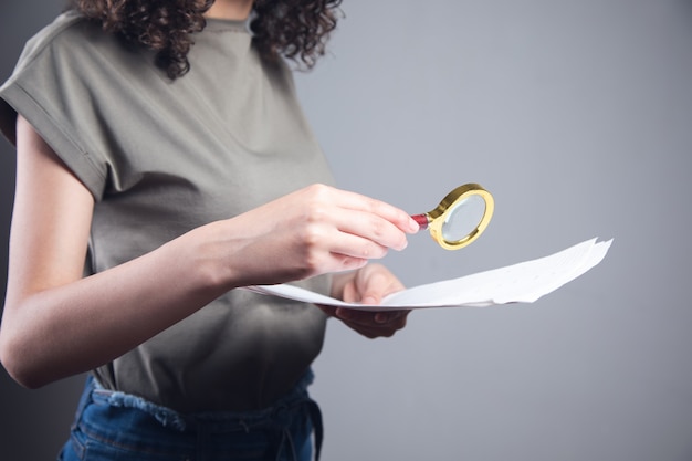A hand holding a magnifying glass over legal documents related to debt and salary embargos in Colombia.
