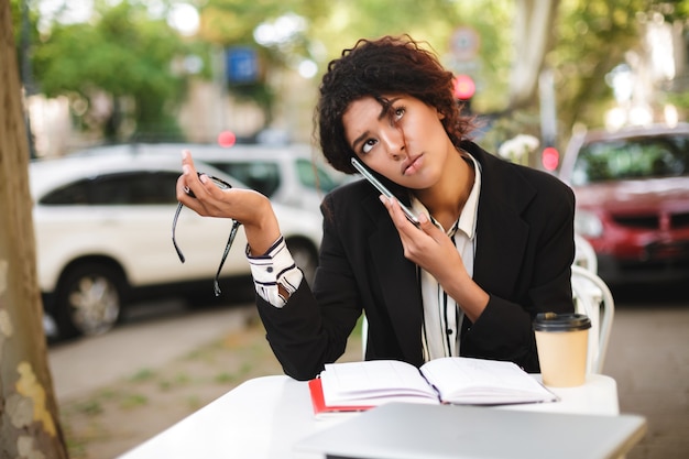 A calm and assertive person talking on the phone with a debt collector, holding a document with 