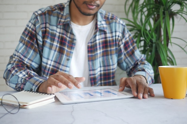 A Colombian entrepreneur meticulously reviewing expenses on a tablet, with charts highlighting areas of potential cost reduction.