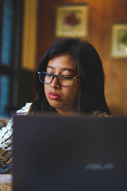 A close-up shot of a Colombian entrepreneur working on their laptop, surrounded by documents and financial reports, with a determined and focused expression. The soft lighting highlights the entrepreneurial spirit and dedication.