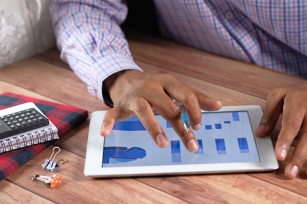 A Colombian entrepreneur using a tablet to manage employee schedules and payroll, with charts and graphs displayed on the screen to illustrate the impact of the labor reform.