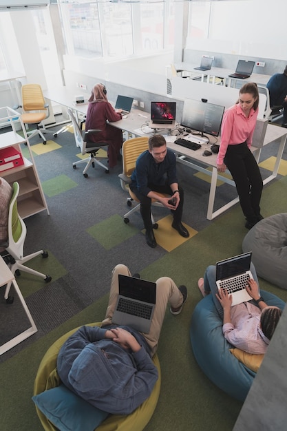 An aerial view of a modern coworking space in Bogotá, Colombia, filled with people working on laptops and tablets. The atmosphere is collaborative and relaxed.